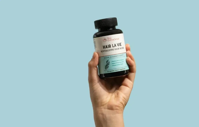 Hair La Vie Revitalizing Blend bottle held in a hand